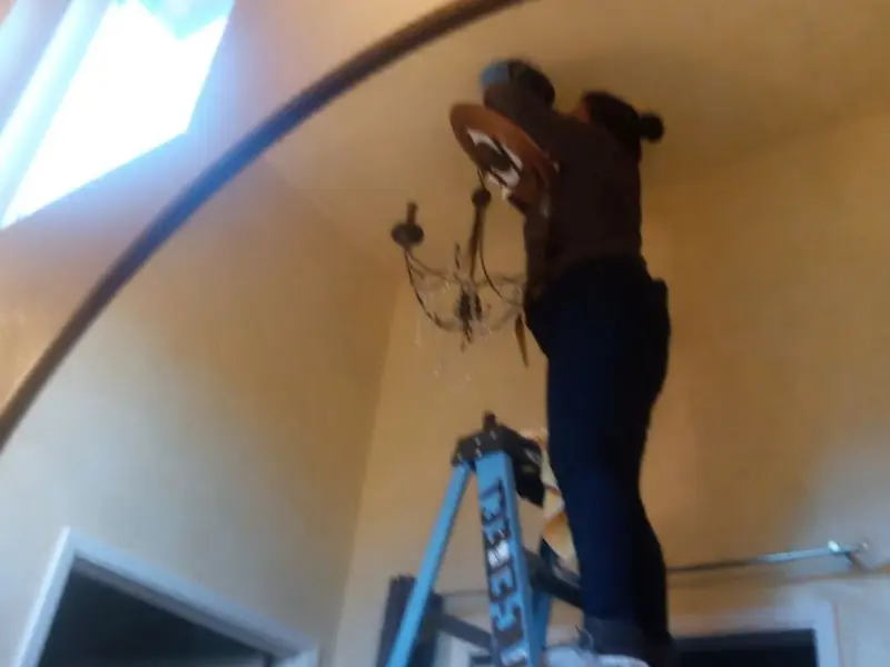 Electrician installing a chandelier in a Hanover residence